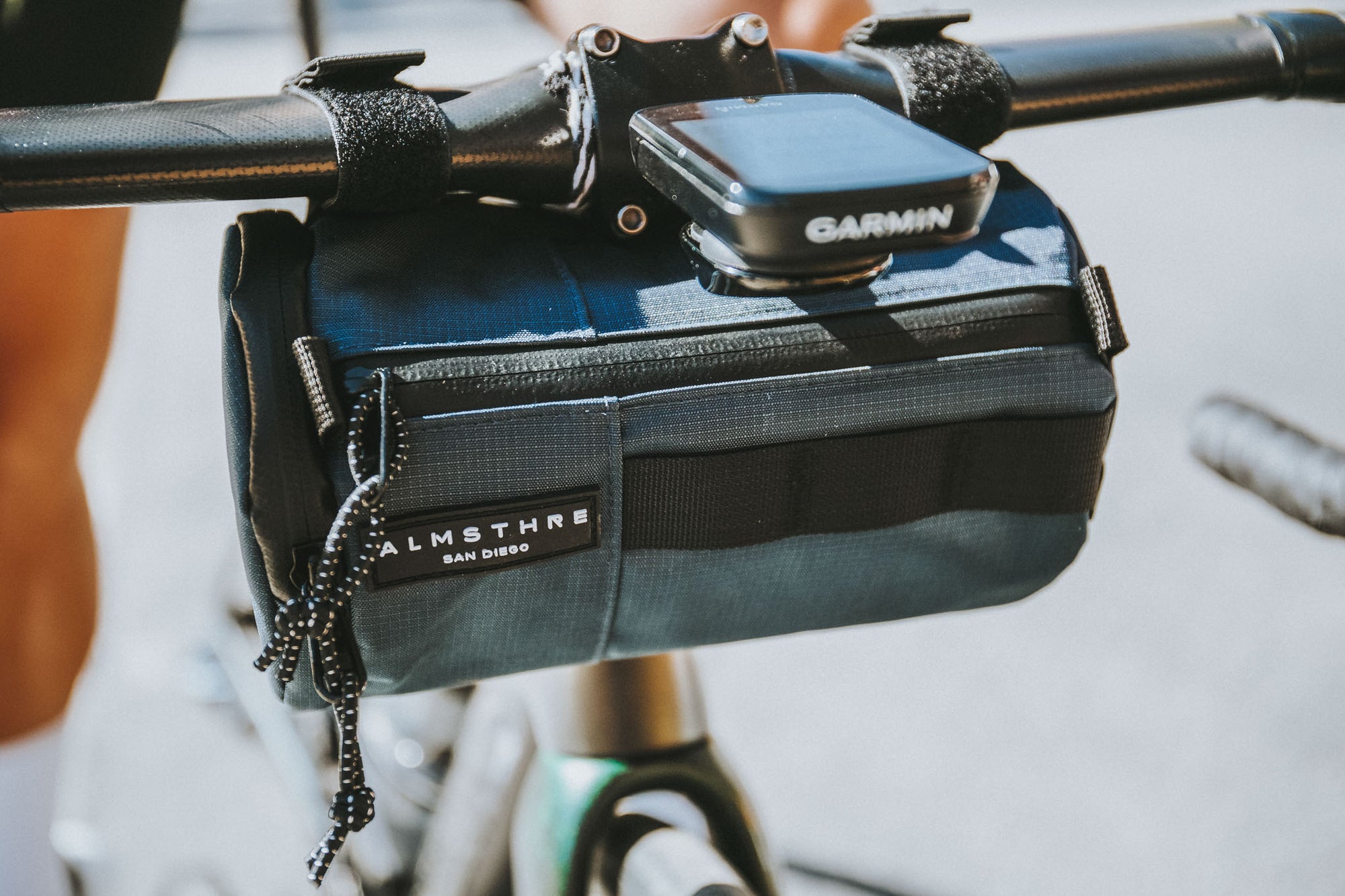 ALMSTHRE full-sized cycling handlebar bag designed for adventure, featuring weatherproof material and waterproof zippers. The Navy Blue bag is securely mounted on the handlebars, ready to accompany cyclists on their outdoor pursuits.